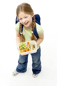 Studio Portrait of Smiling Girl Holding Lunchbox
