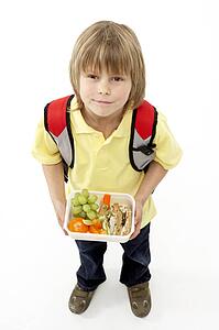Studio Portrait of Smiling Boy Holding Lunchbox