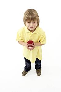 Studio Portrait of Smiling Boy Holding Glass of Fruit Juice
