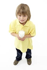 Studio Portrait of Smiling Boy Holding Glass of Milk