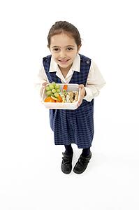 Studio Portrait of Smiling Girl Holding Lunchbox
