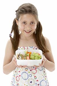 Studio Portrait of Smiling Girl Holding Lunchbox