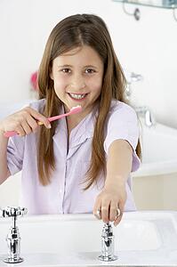 Young Girl Brushing Teeth at Sink
