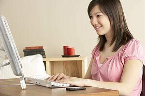 Smiling Teenage Girl on Computer at Home