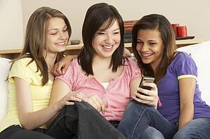 Teenage Girlfriends Reading Mobile Phone at Home