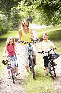 Mother and children riding bikes in countryside