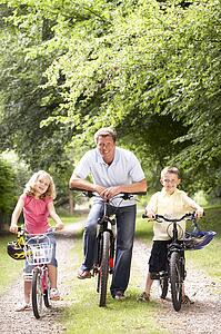 Father and children riding bikes in countryside