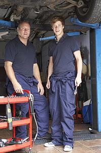 Mechanic and apprentice working on car