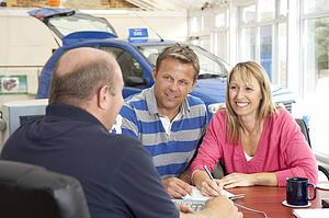 Couple filling in paperwork in car showroom