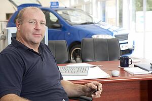 Car salesman sitting in showroom