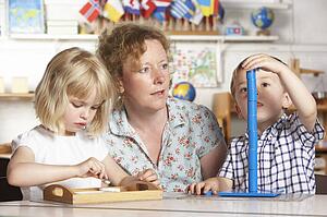 Adult Helping Two Young Children at Montessori/Pre-School