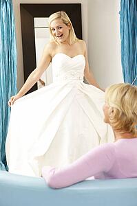 Bride trying on wedding dress with sales assistant