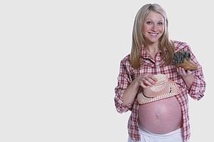 Pregnant woman holding little clothes