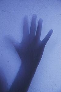 Silhouette of open hand against wall