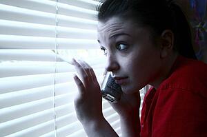 Teenage girl on the phone, peeking out the window