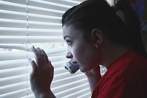 Teenage girl on the phone, peeking out a window