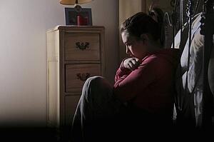 Teenage girl sitting at the foot of her bed
