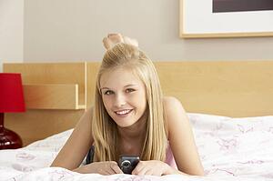 Teenage Girl In Bedroom With Mobile Phone