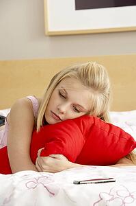 Sad Teenage Girl In Bedroom With Mobile Phone