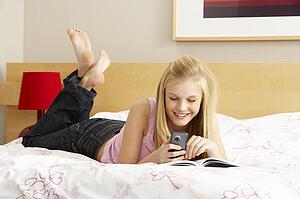Teenage Girl Writing In Diary In Bedroom