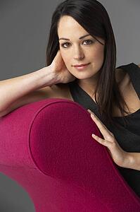 Studio Portrait Of Woman Relaxing On Pink Chaise Longue