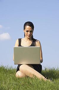 Woman Using Laptop Outdoors In Summer Countryside