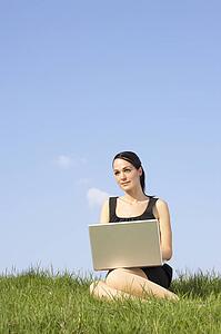 Woman Using Laptop Outdoors In Summer Countryside