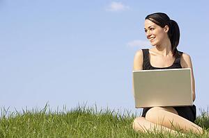 Woman Using Laptop Outdoors In Summer Countryside