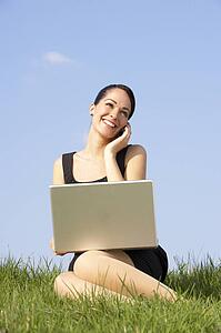 Woman Using Laptop And Mobile Phone Outdoors In Countryside