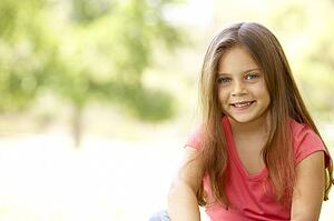 Portrait Of Young Girl Sitting In Park