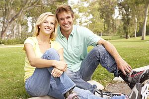 Couple Putting On In Line Skates In Park