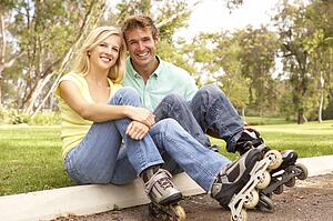 Couple Putting On In Line Skates In Park