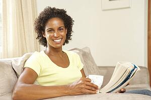 Woman Reading Book With Drink At Home