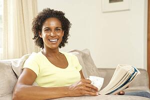 Woman Reading Book With Drink At Home
