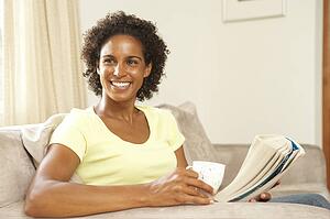 Woman Reading Book With Drink At Home
