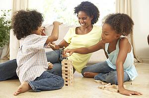 Brother And Sister Playing Game With Mother At Home
