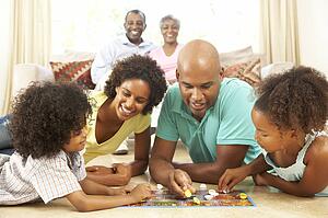 Family Playing Board Game At Home With Grandparents Watching