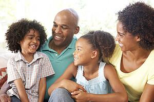 Young Family Relaxing On Sofa At Home
