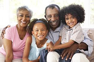 Grandparents With Grandchildren Relaxing On Sofa At Home Together