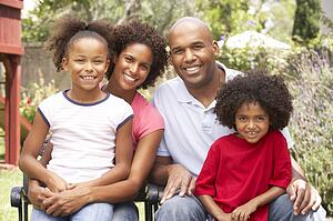 Young Family Relaxing In Garden Together