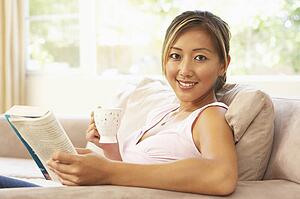 Woman Reading Book With Drink At Home