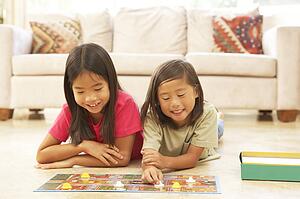 Two Girls Playing Board Game At Home