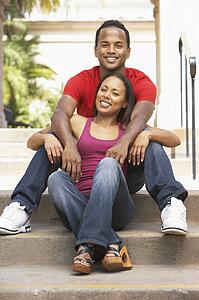 Young Couple Sitting On Steps Of Building