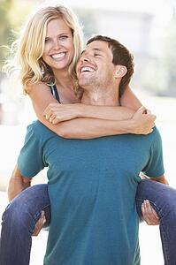 Young Man Giving Woman Piggyback Outdoors