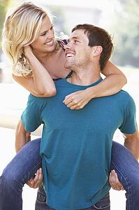Young Man Giving Woman Piggyback Outdoors