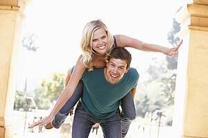 Young Man Giving Woman Piggyback Outdoors