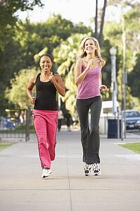 Two Female Friends Jogging On Street