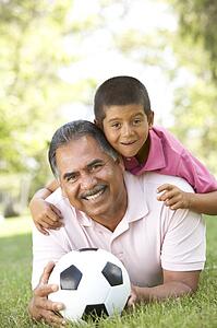 Grandfather With Grandson In Park With Football