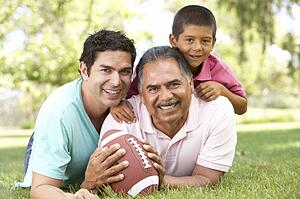 Grandfather With Son And Grandson In Park With American Football