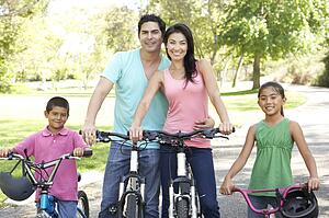 Young Family Riding Bikes In Park